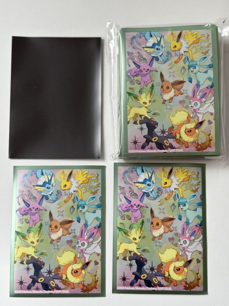 Koszulki na karty z zestawu Prismatic Evolutions – awers z czarnym wnętrzem, rewers z grafiką Eevee i ewolucji